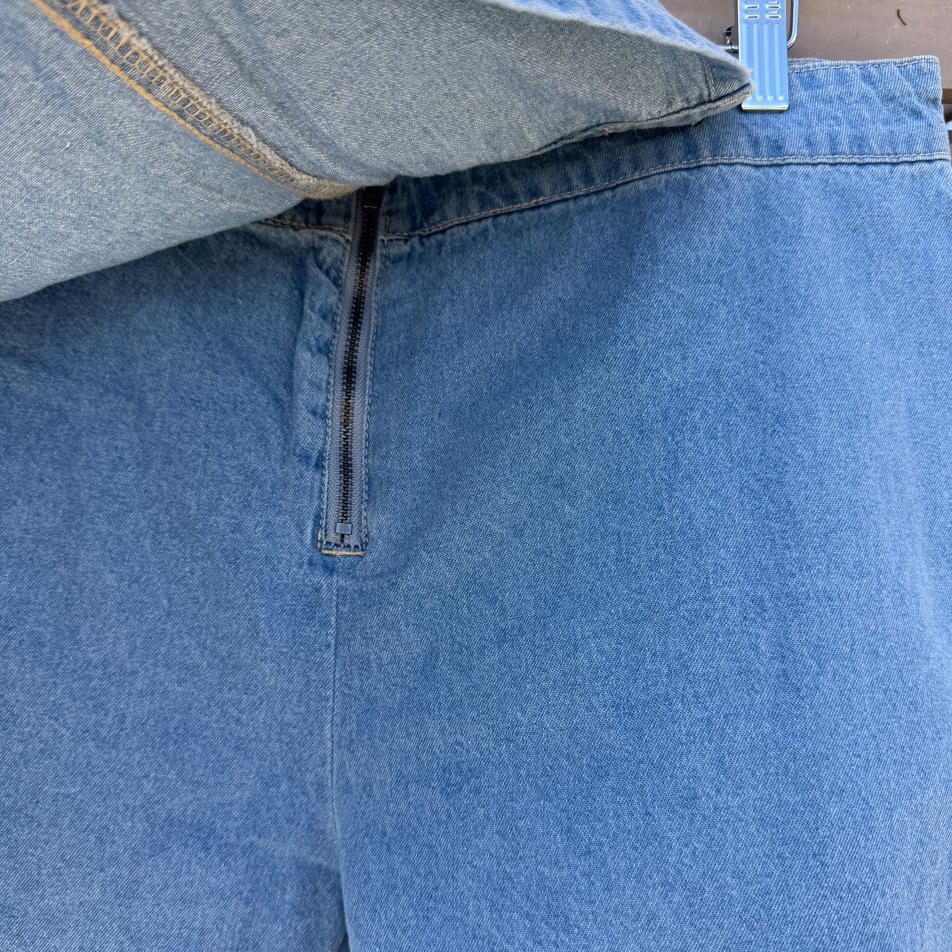 Close-up of blue denim shorts with a zipper on a wooden surface