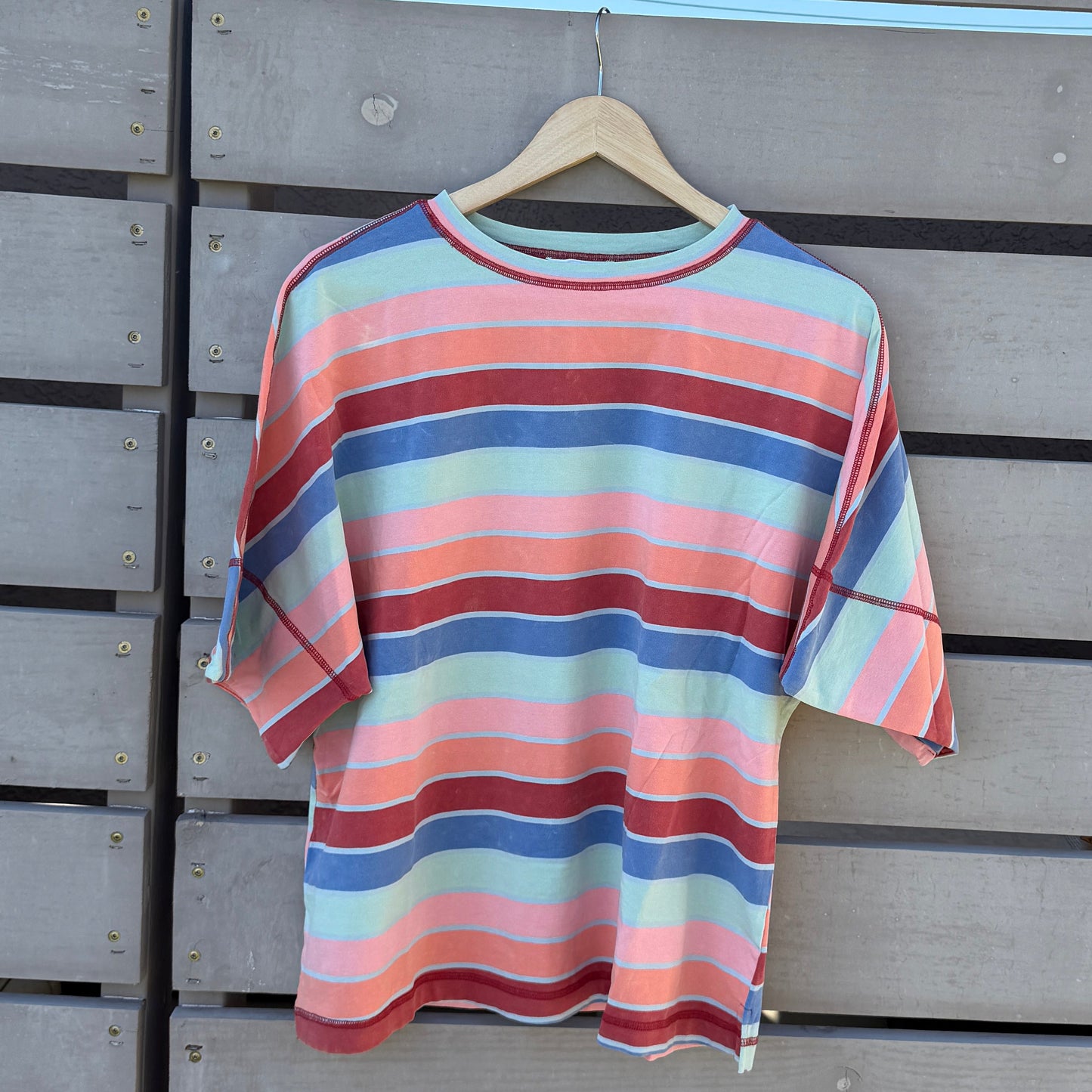 Striped shirt hanging on a wooden wall with a blue sky background
