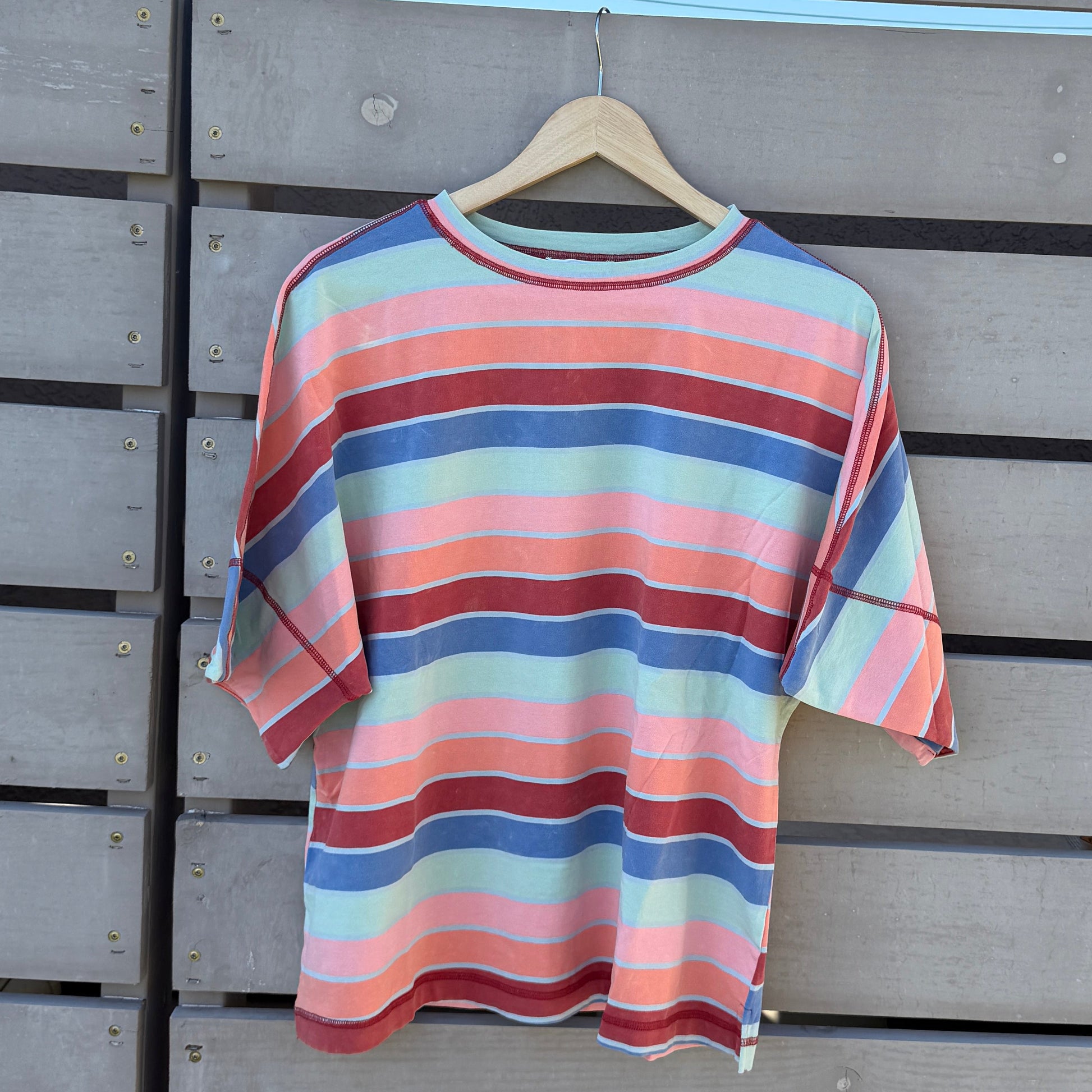 Striped shirt hanging on a wooden wall with a blue sky background