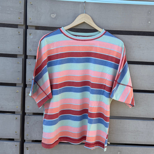 Striped shirt hanging on a wooden wall with a blue sky background