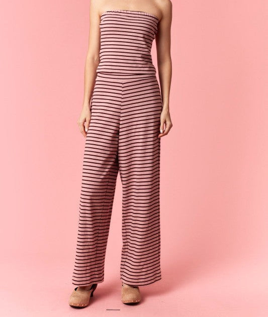 Woman wearing a strapless striped jumpsuit on a pink background