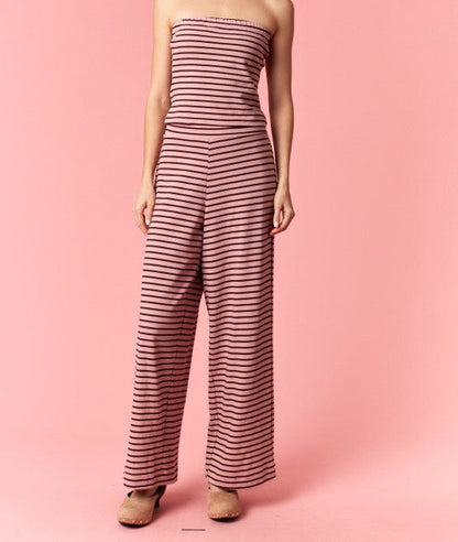 Woman wearing a strapless striped jumpsuit on a pink background