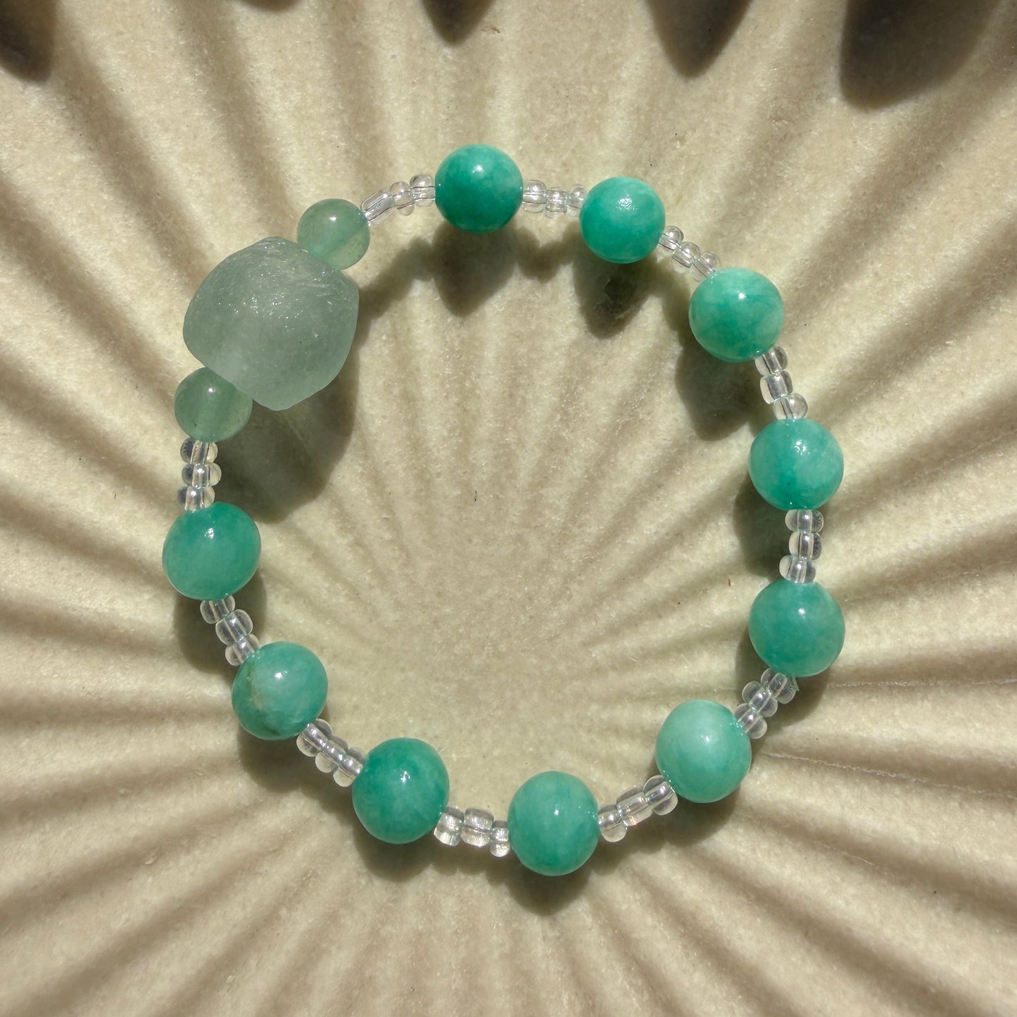 Green beaded bracelet on a textured beige background