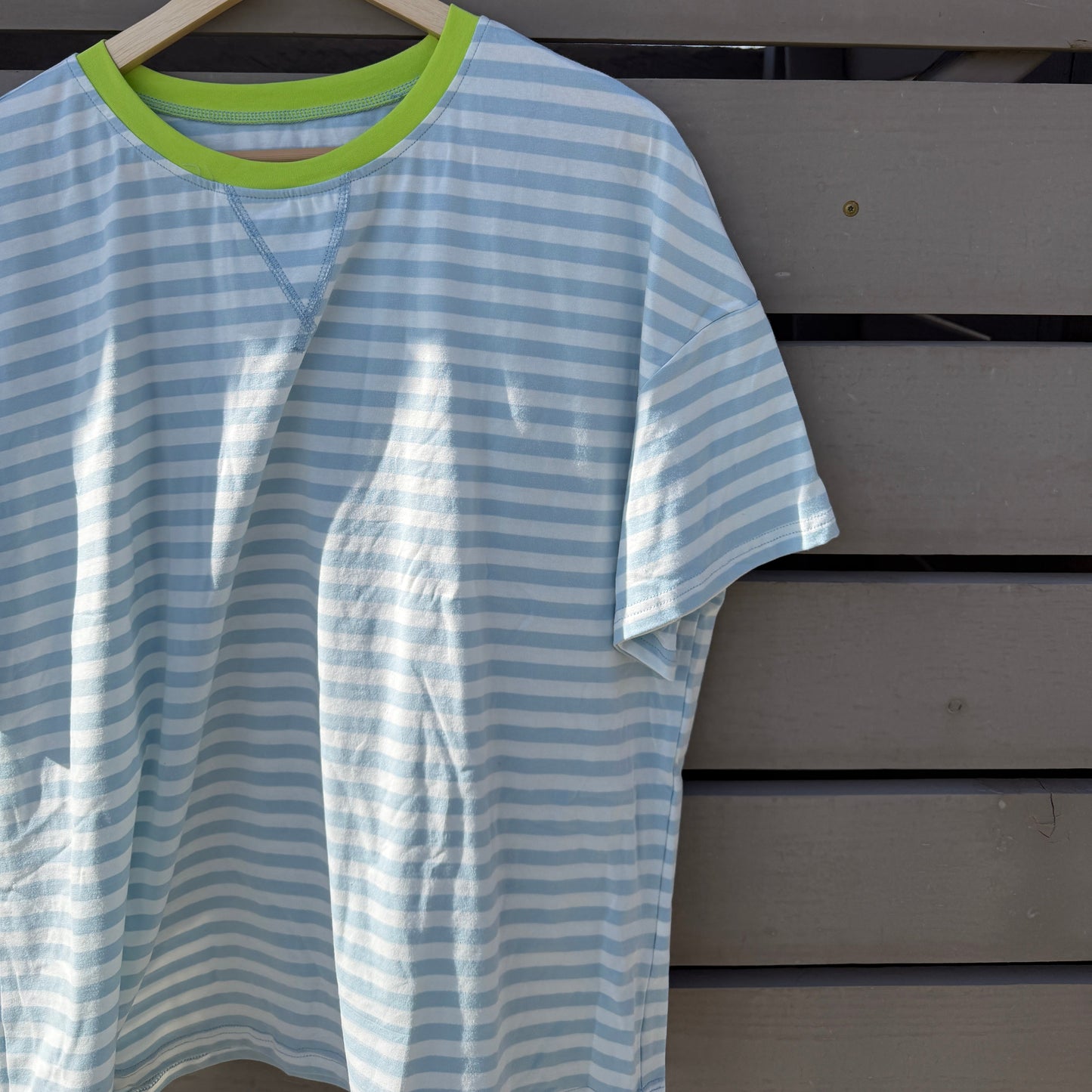 Blue and white striped shirt on a hanger against a wooden background