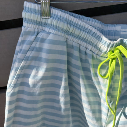 Blue and white striped shorts with a green drawstring hanging on a rack.