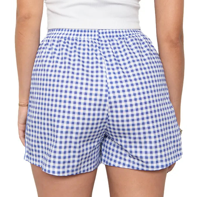 Woman wearing a white sleeveless top and blue checkered shorts on a white background