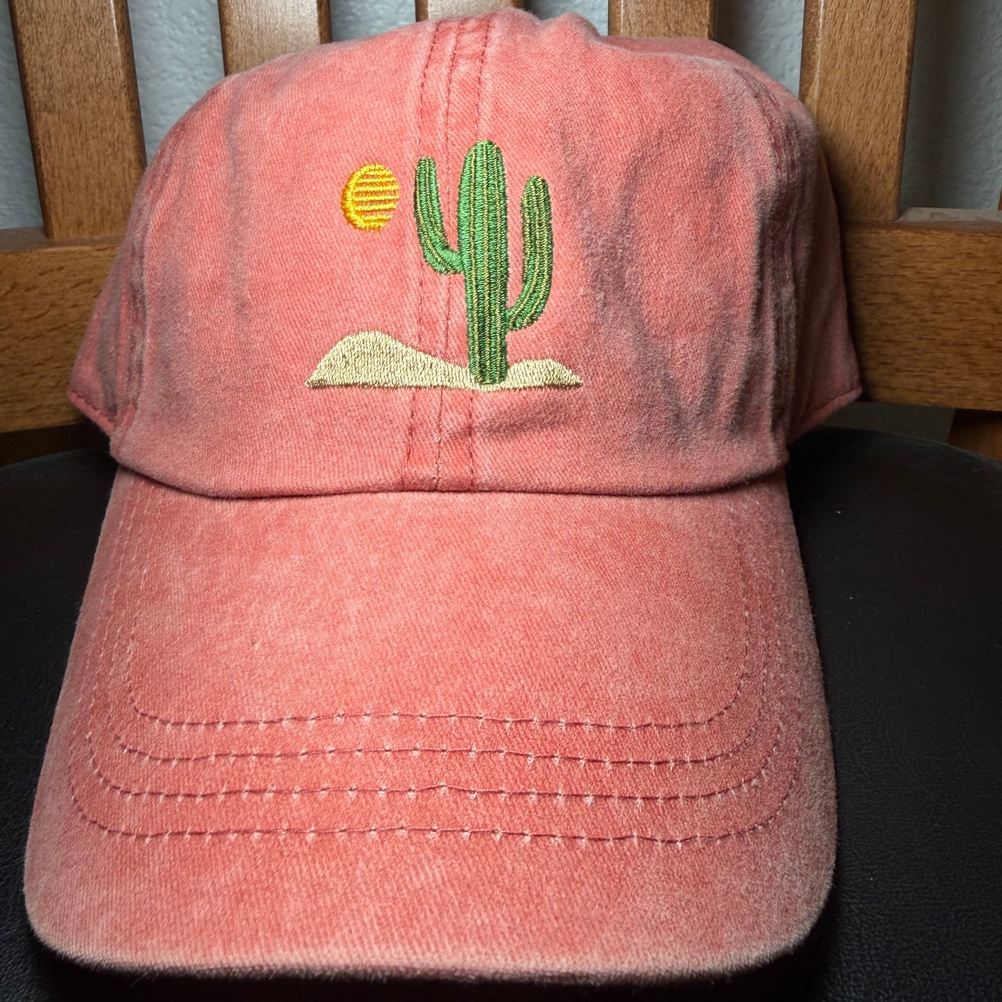 Orange cap with a green cactus design on a wooden surface