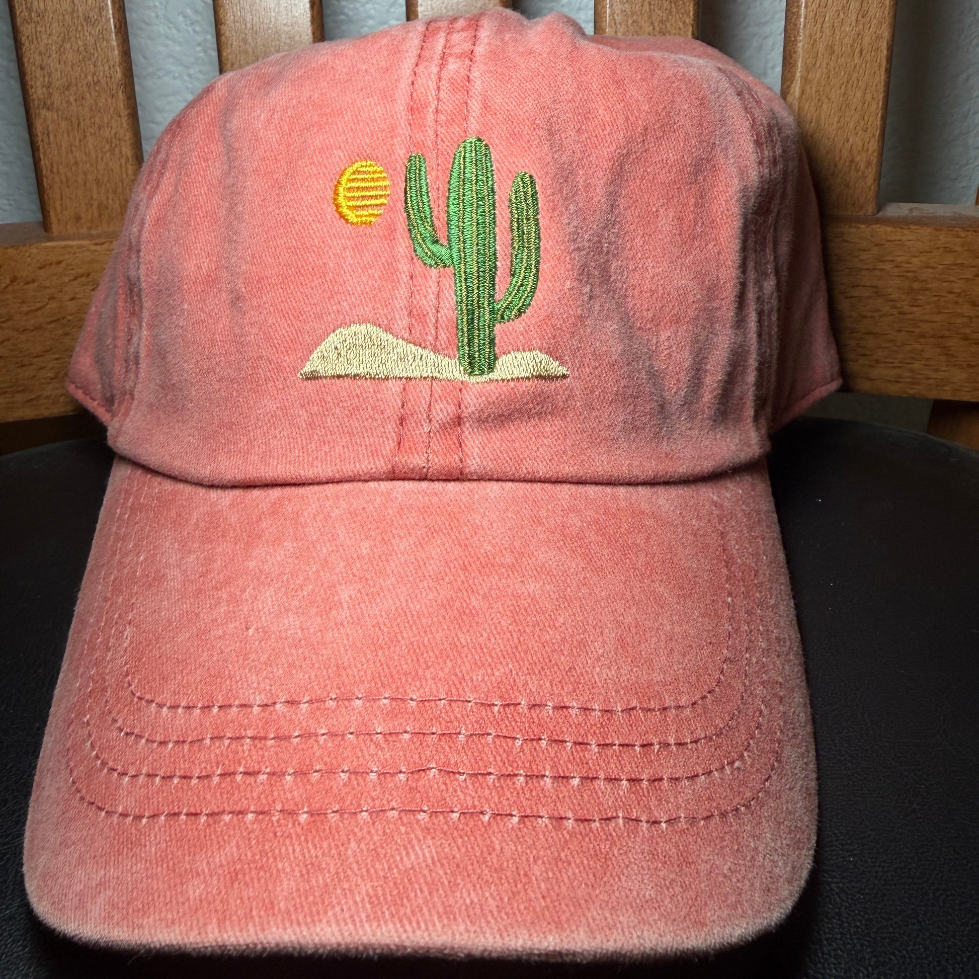 Orange cap with a green cactus design on a wooden surface