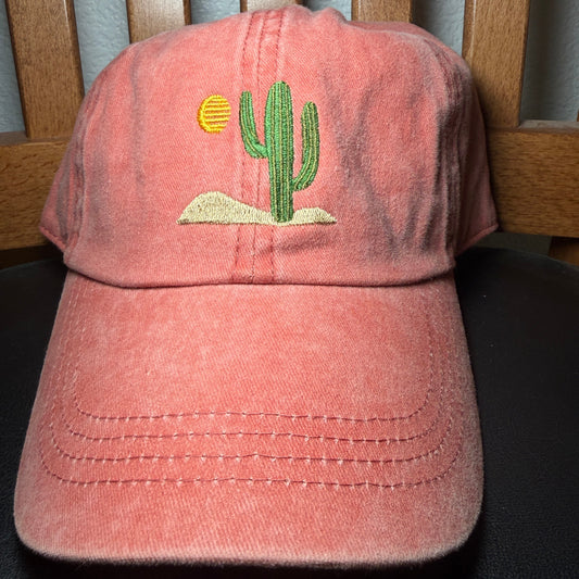 Orange cap with a green cactus design on a wooden surface