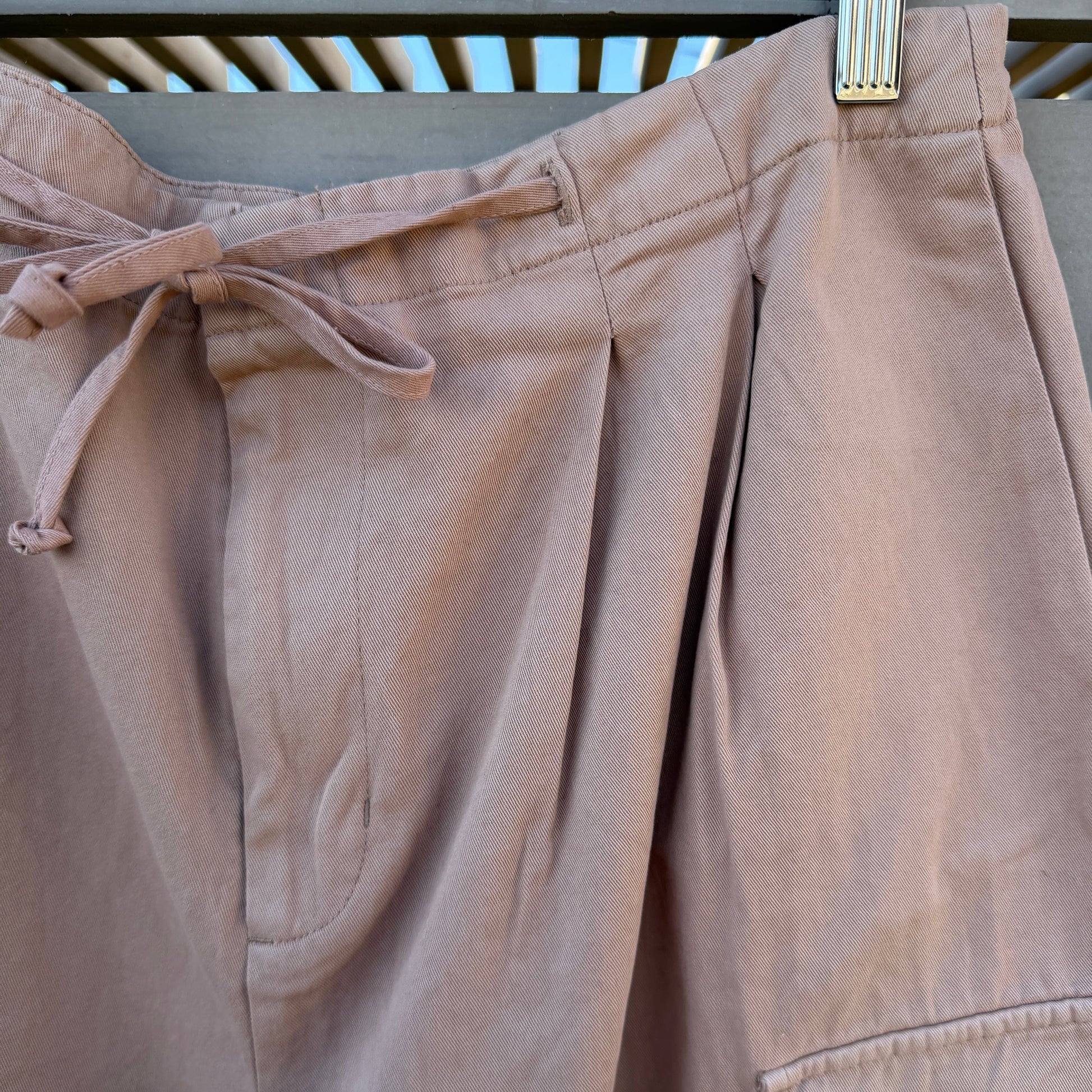 Beige pants hanging on a rack with a neutral background