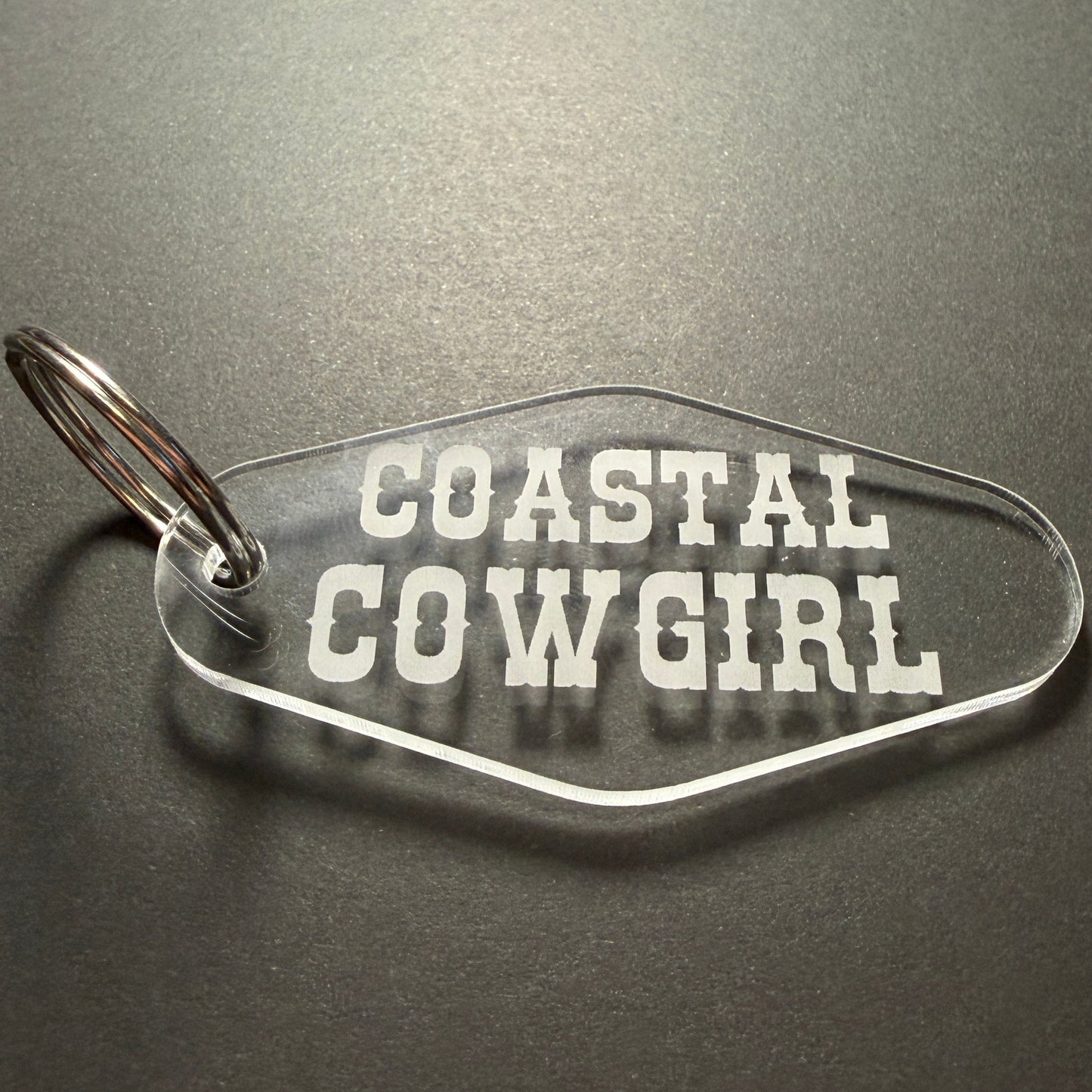 Keychain with 'Coastal Cowgirl' text on a dark surface