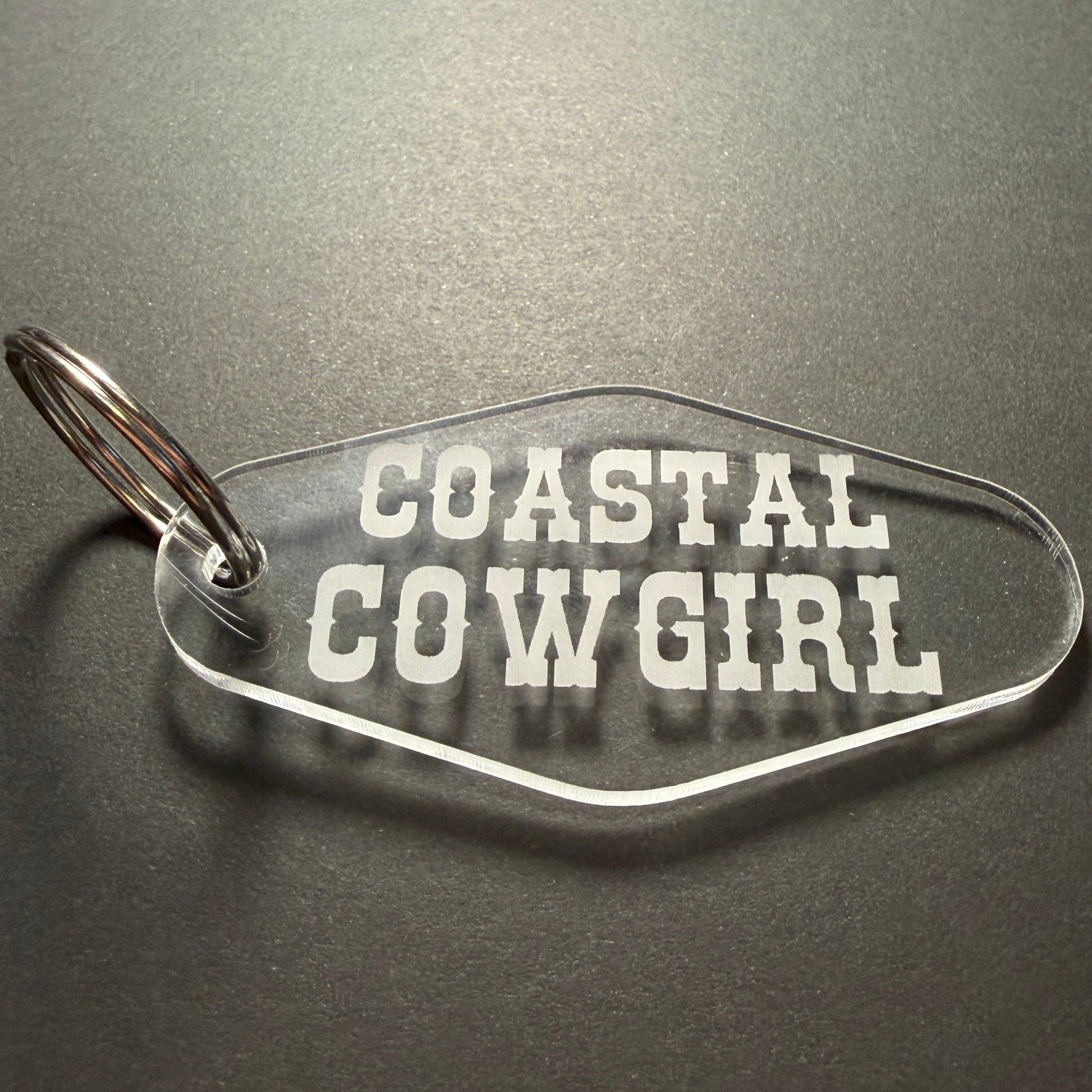 Keychain with 'Coastal Cowgirl' text on a dark surface