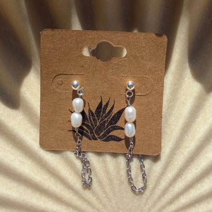 earrings pearls on a cardboard backing against a textured beige background