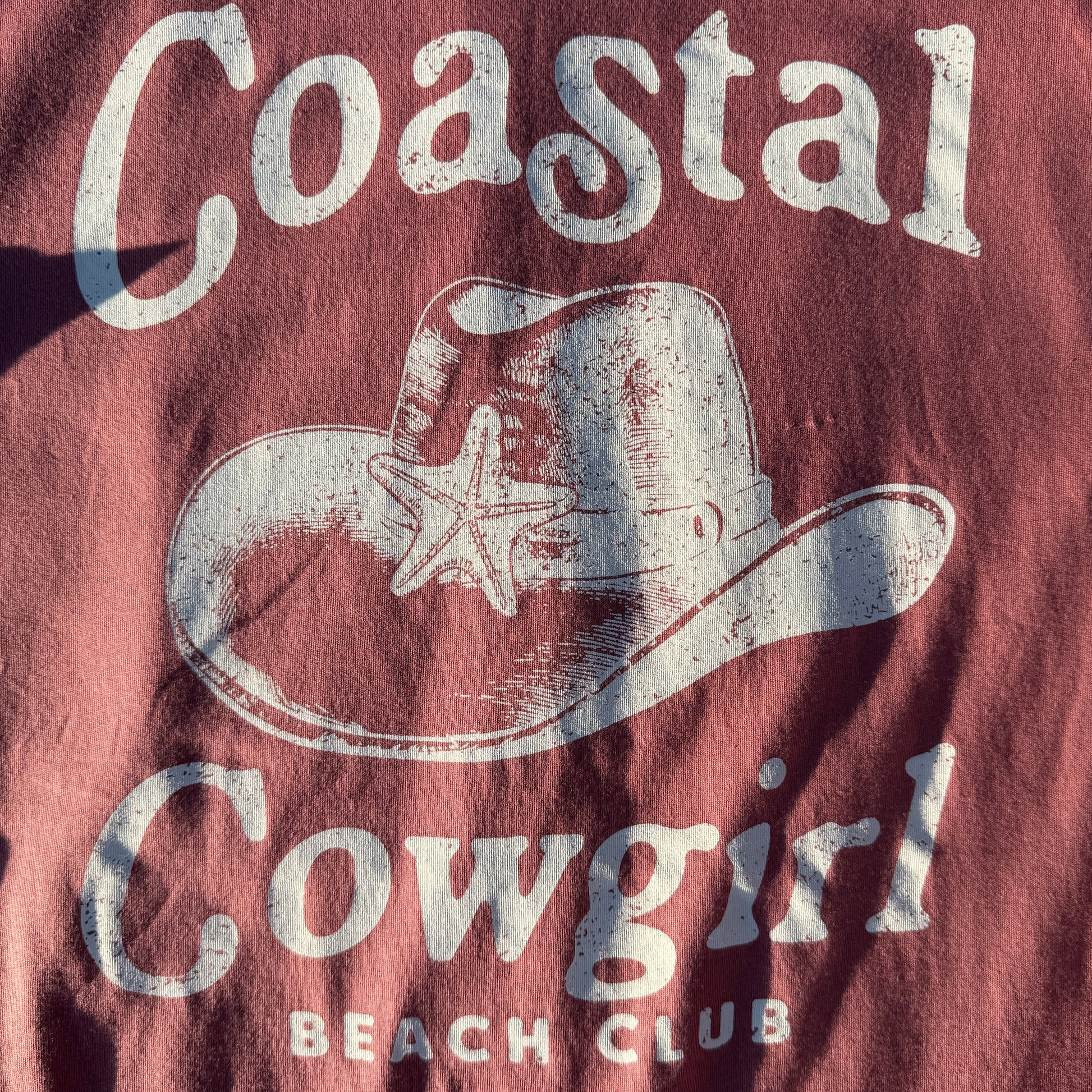 T-shirt with 'Coastal Cowboy' logo and text on a dark background
