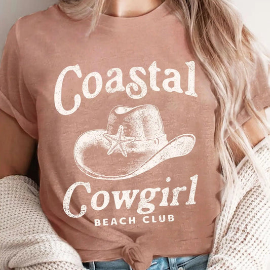 Person wearing a brown t-shirt with 'Coastal Cowgirl Beach Club' text and graphic.