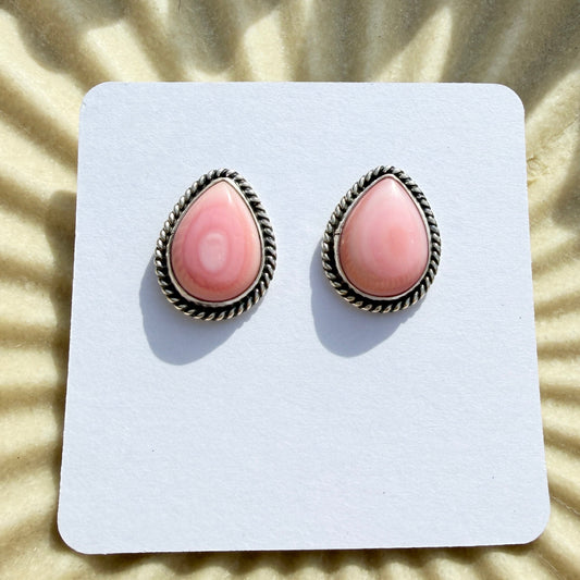 Pair of pink teardrop earrings on a white card with a sunburst background