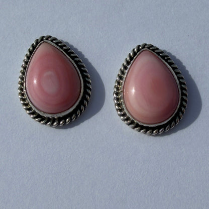 Pair of pink earrings on a white card with a gray background