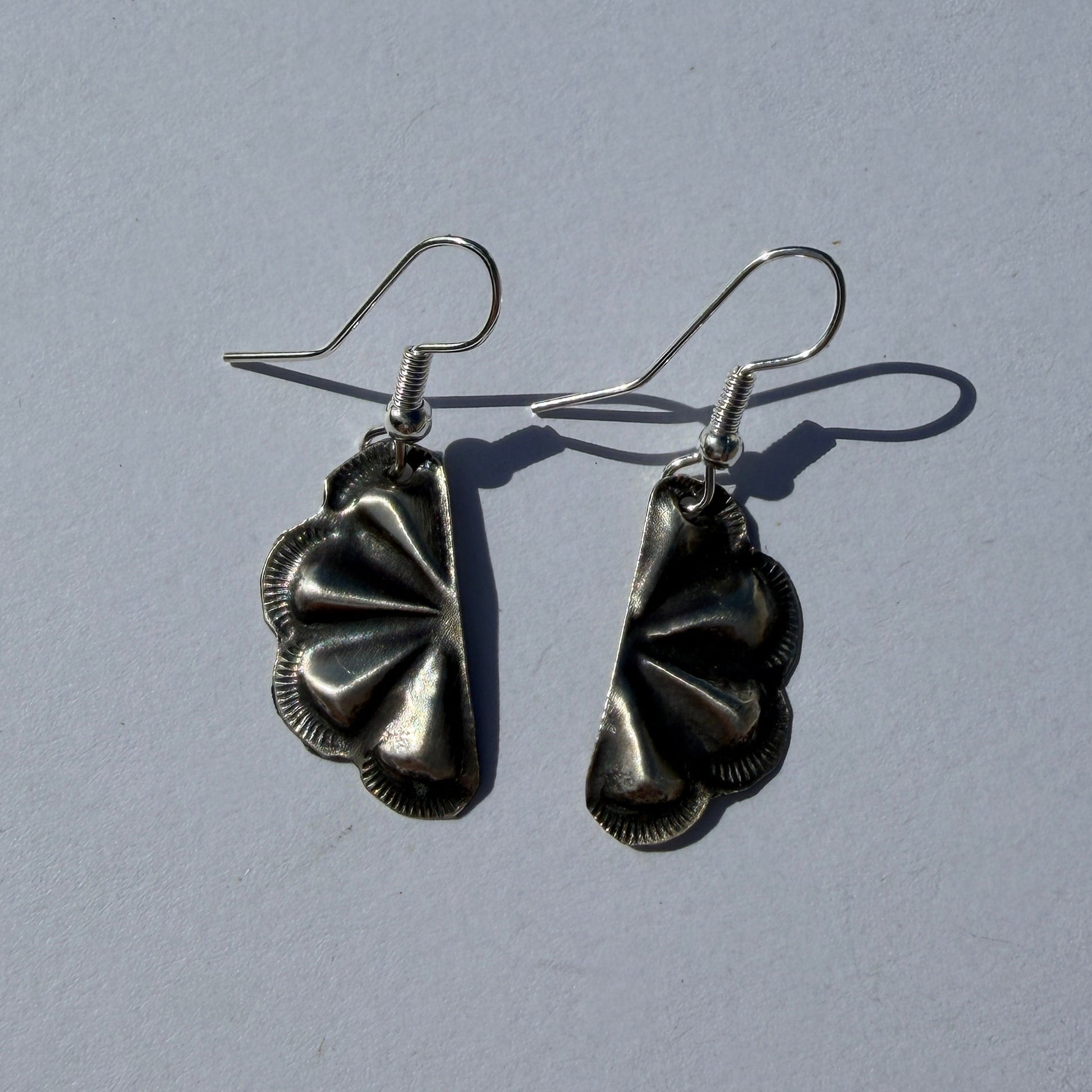 Pair of silver floral earrings on a light gray background