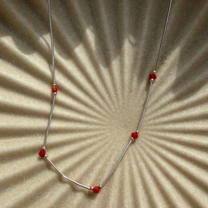 Necklace with red beads on a textured beige surface