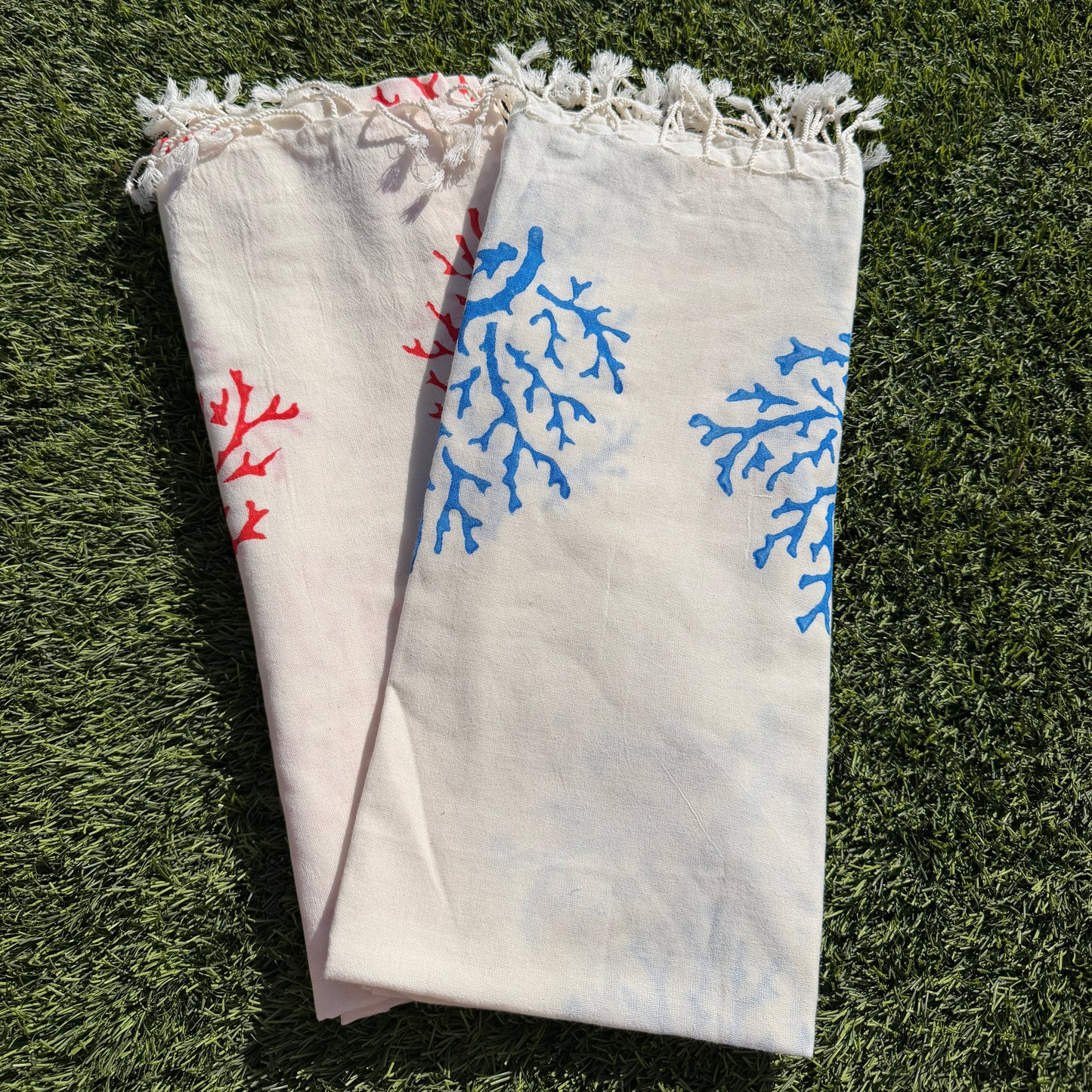 Folded towel with blue and red floral patterns on a grassy background