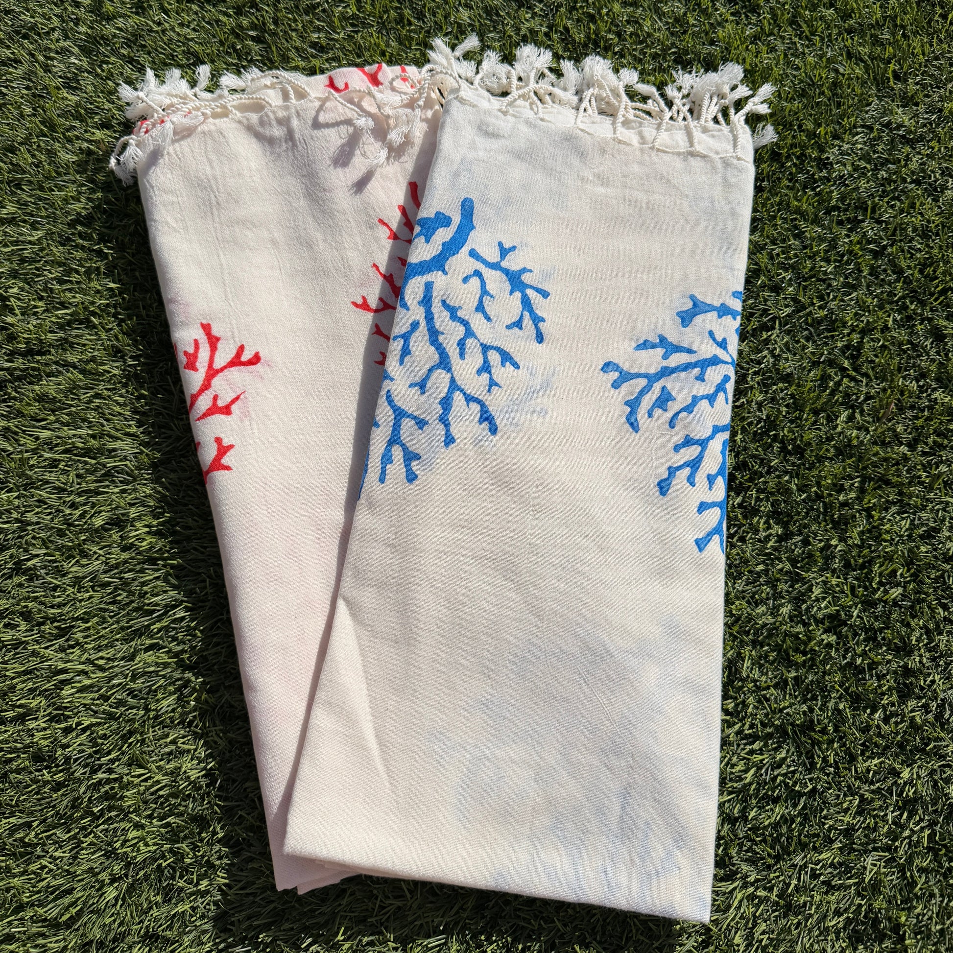 Folded towel with blue and red floral patterns on a grassy background