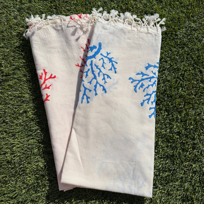 Folded towel with blue and red floral patterns on a grassy background