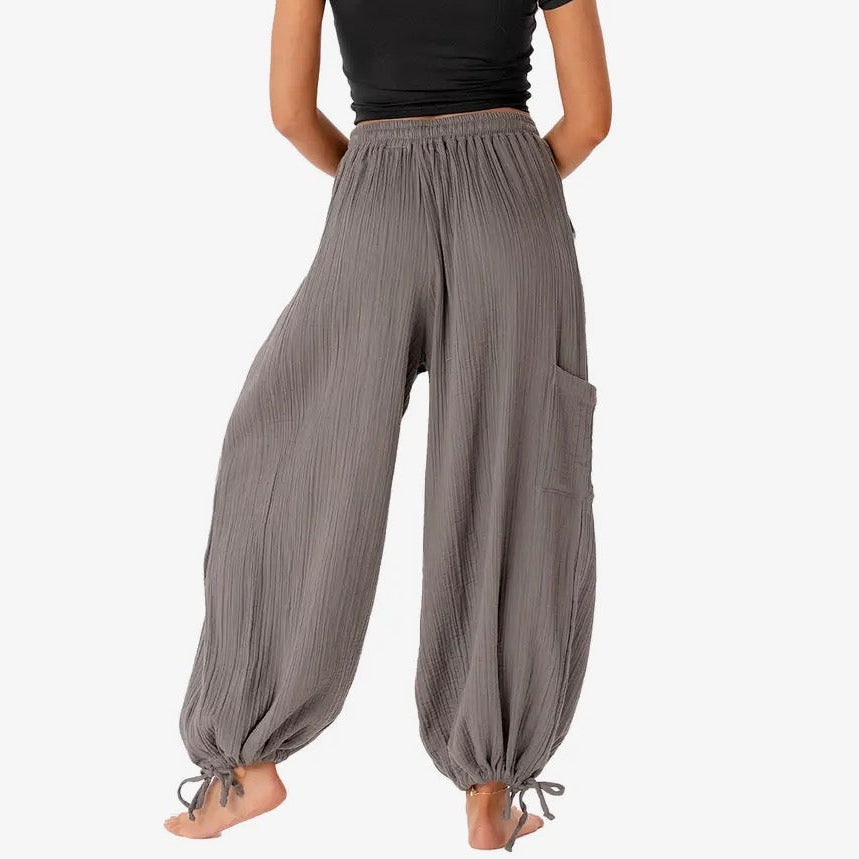 Woman wearing gray wide-leg pants and a black top on a white background