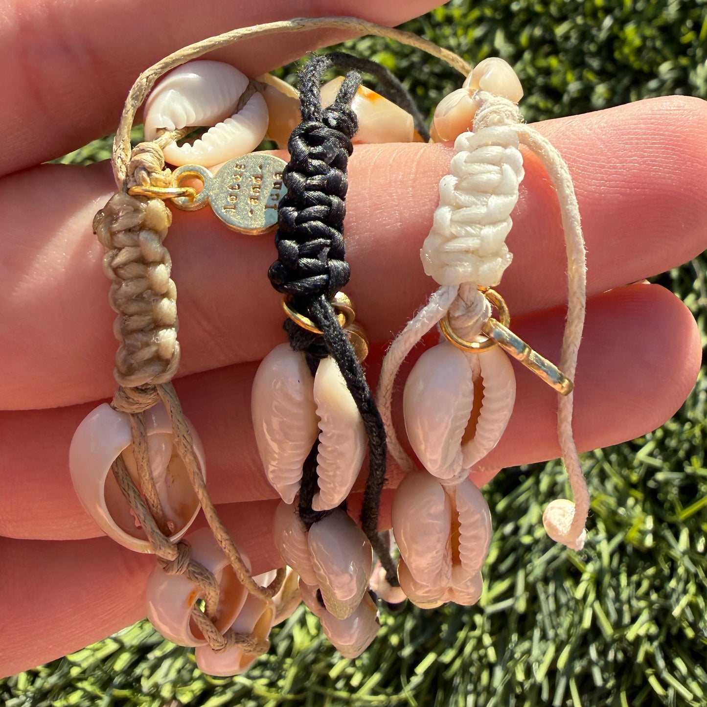 Hand holding multiple bracelets with a grass background