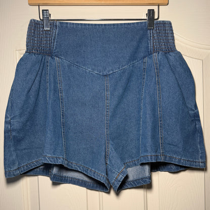 Folded blue denim jeans on a wooden hanger against a beige wall.