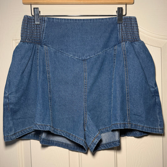 Folded blue denim jeans on a wooden hanger against a beige wall.