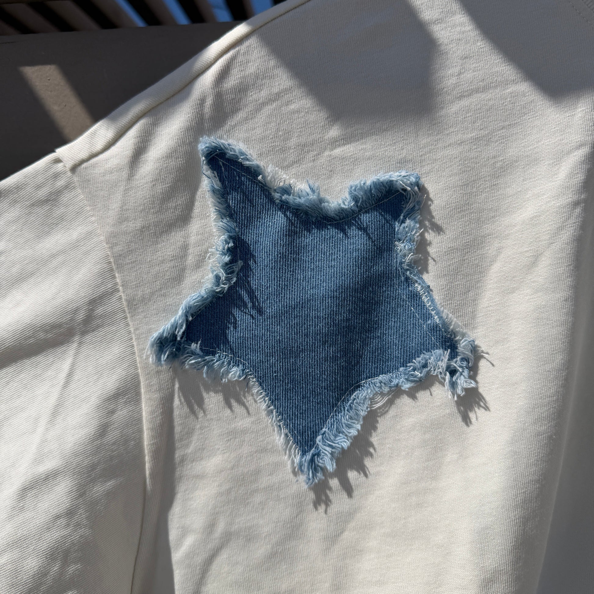 Blue denim patch on a white shirt with sunlight casting shadows