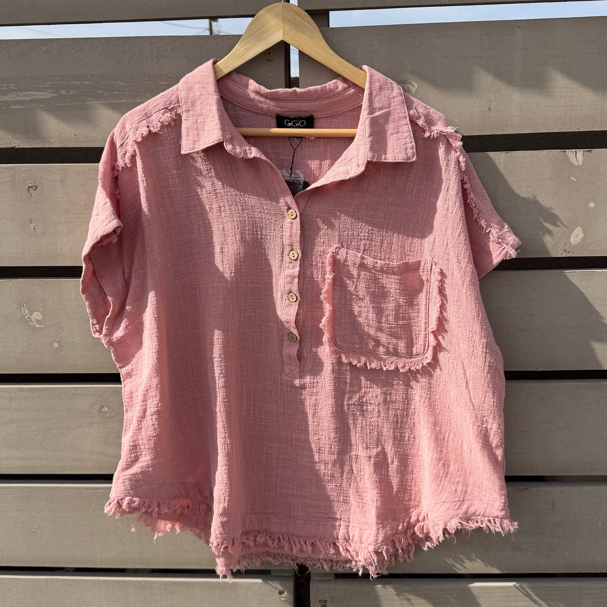 Pink shirt on a hanger against a wooden panel background