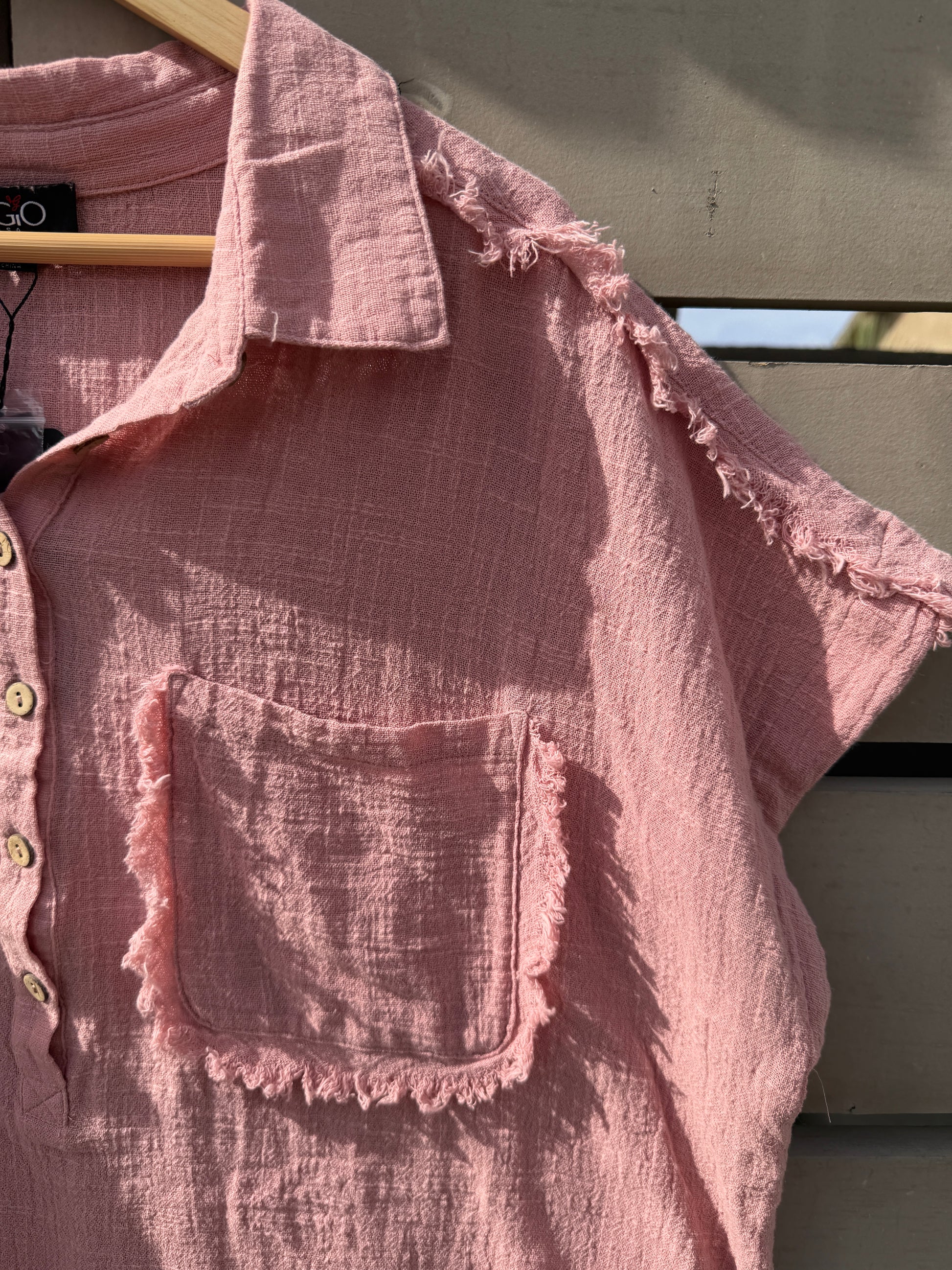 Pink textured shirt with ruffled edges on a dark background