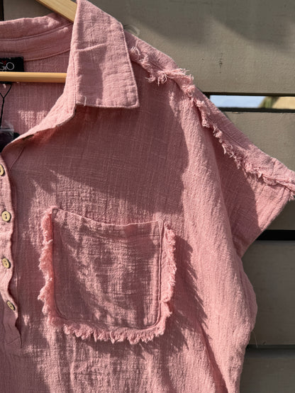 Pink textured shirt with ruffled edges on a dark background