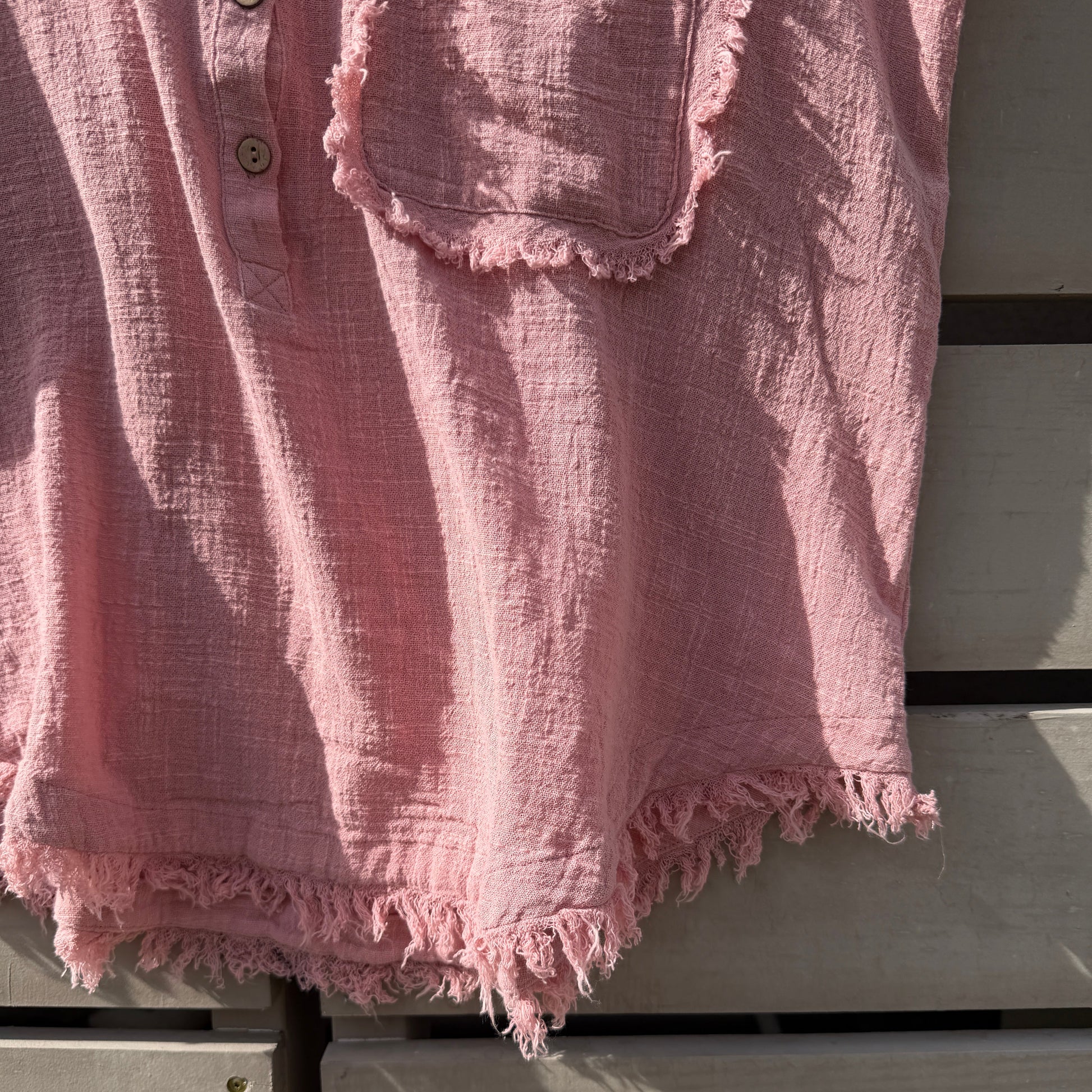 Pink textured fabric with frayed edges on wooden surface