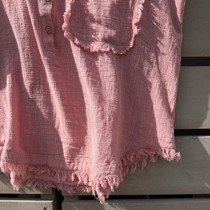 Pink textured fabric with frayed edges on wooden surface