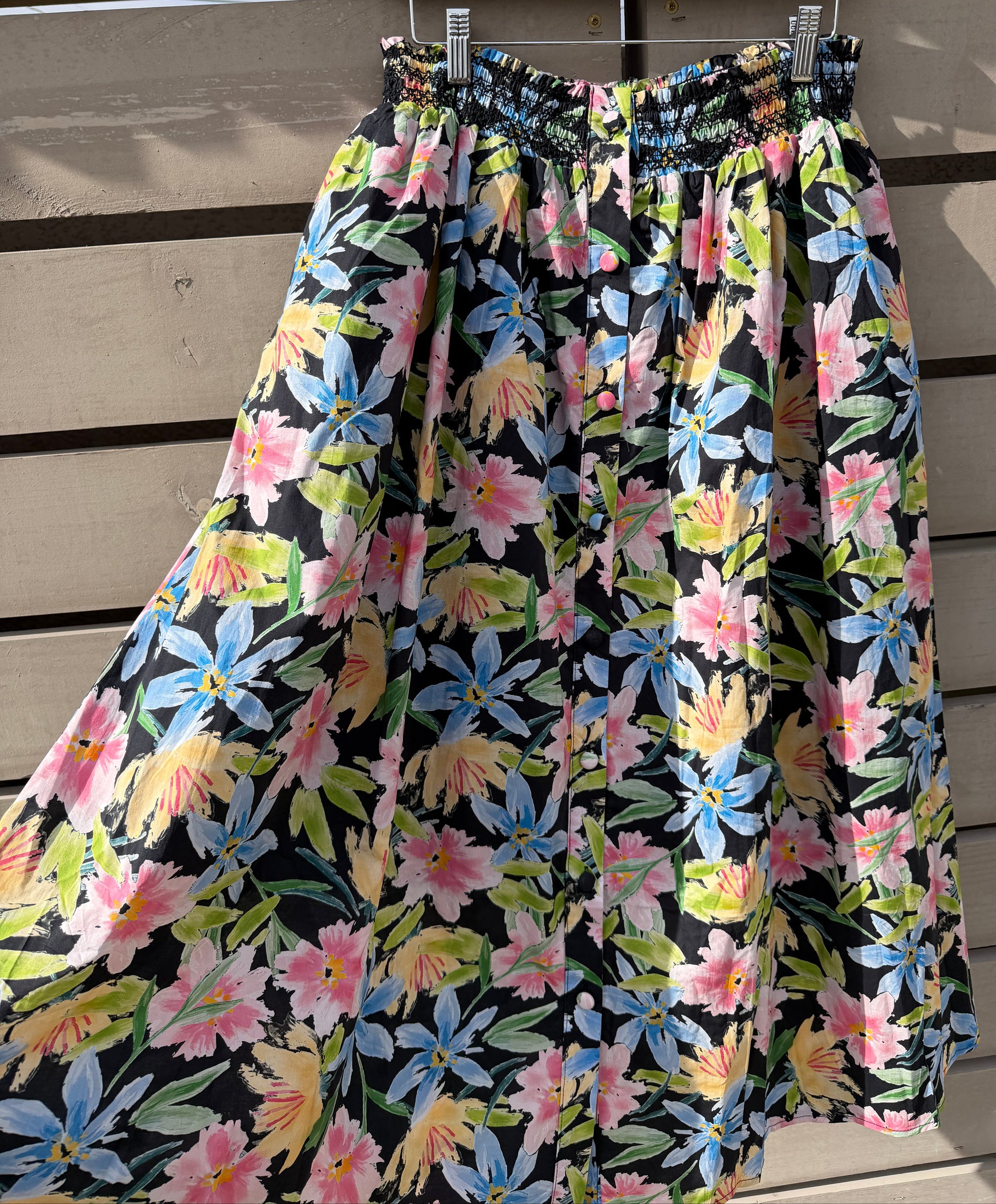 Floral-patterned fabric on a wooden rod against a wooden background