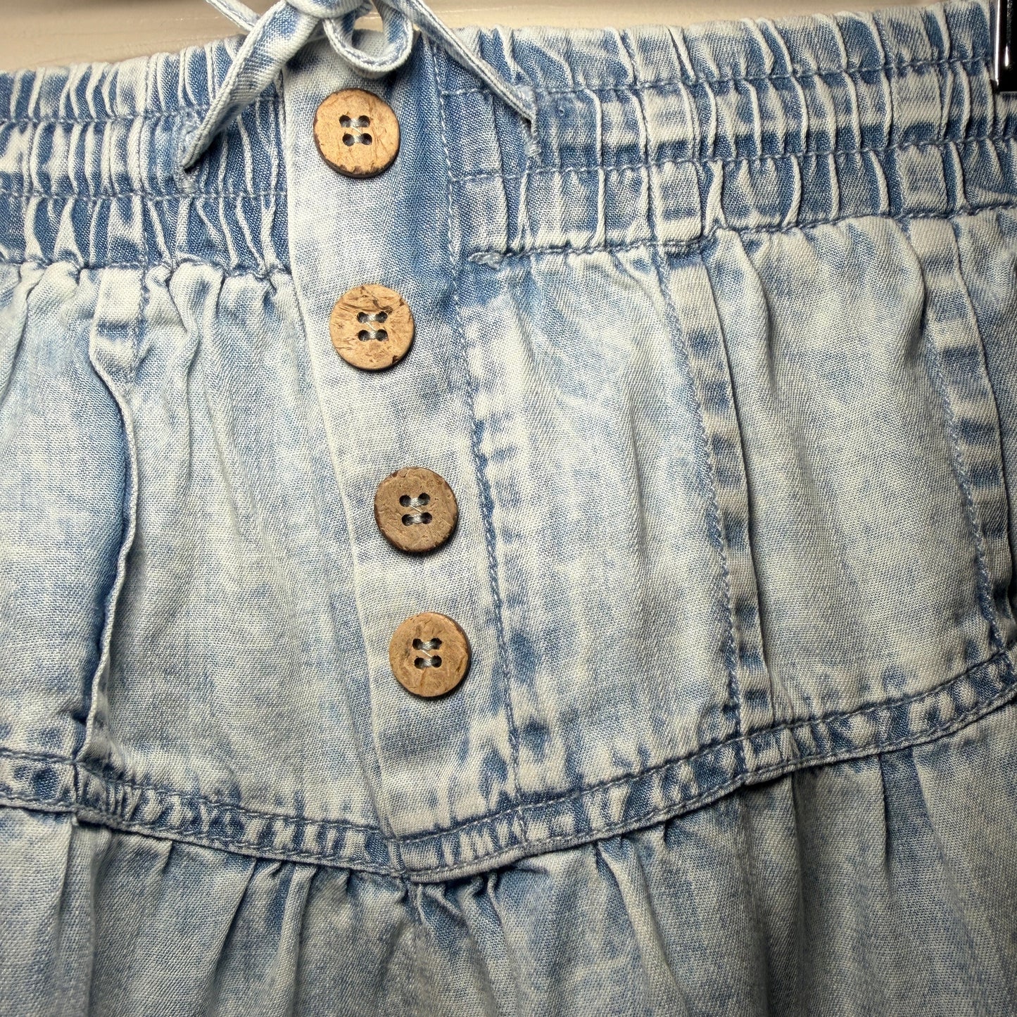 Close-up of a denim shorts with wooden buttons on a plain background
