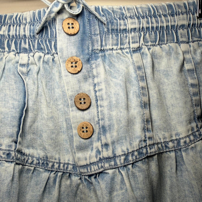 Close-up of a denim shorts with wooden buttons on a plain background