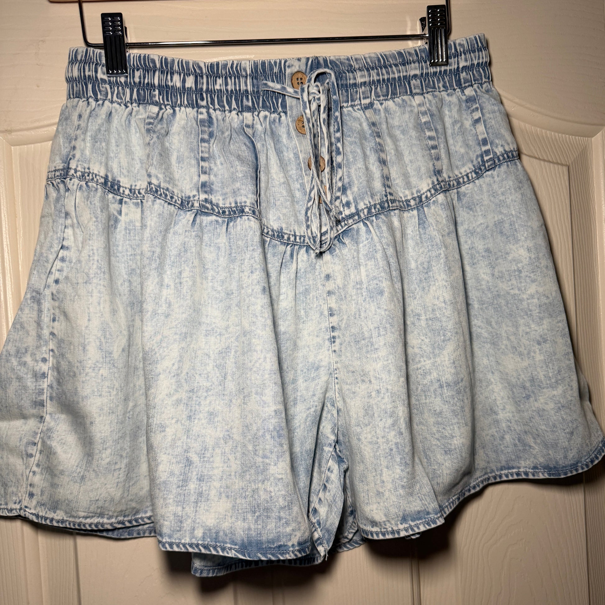 Folded denim skirt on a wooden hanger against a neutral background