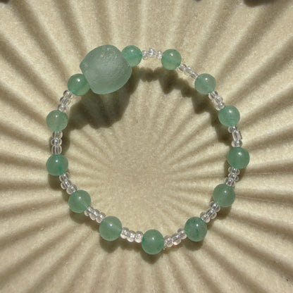 Green beaded bracelet on a textured beige background