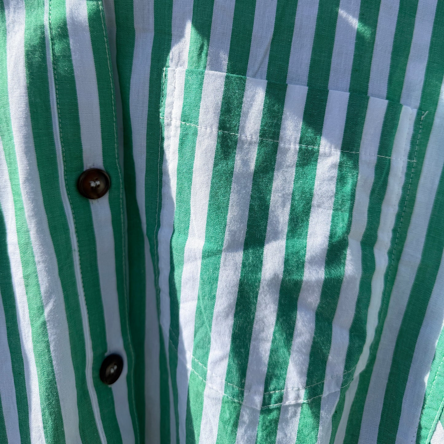 Close-up of a green and white striped shirt with buttons.