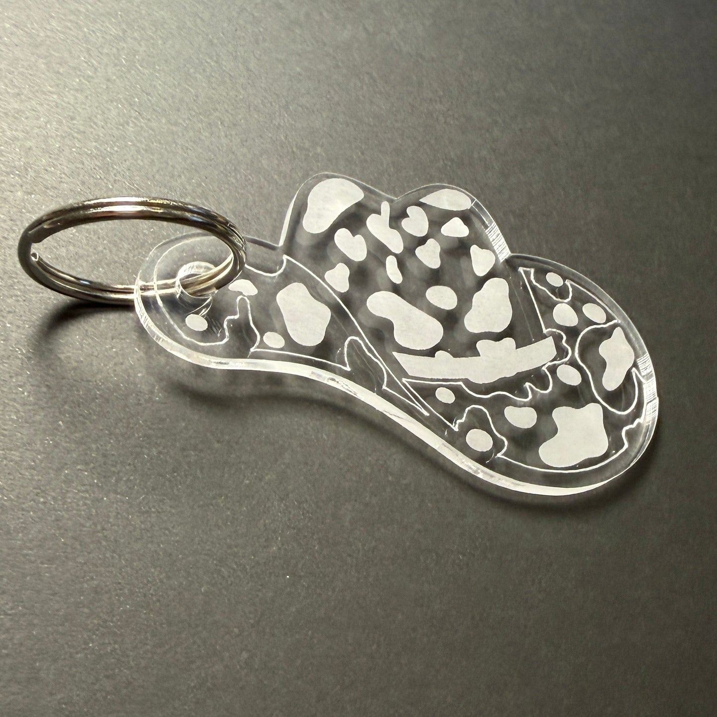 Metallic keychain with a hatdesign on a dark surface