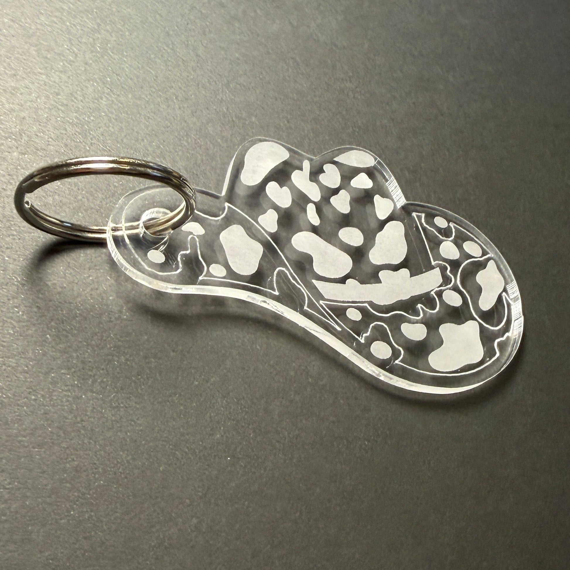 Metallic keychain with a hatdesign on a dark surface