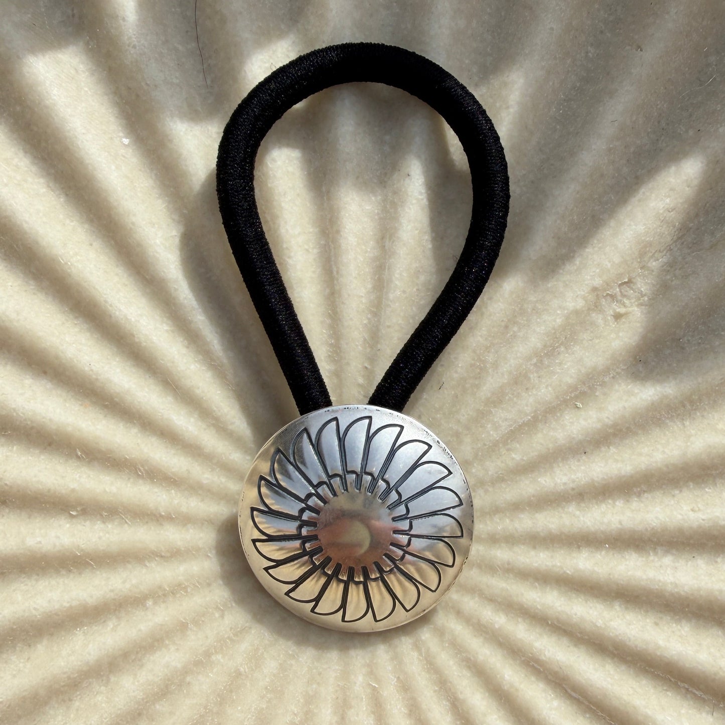 Hair tie with decorative button on a textured beige background