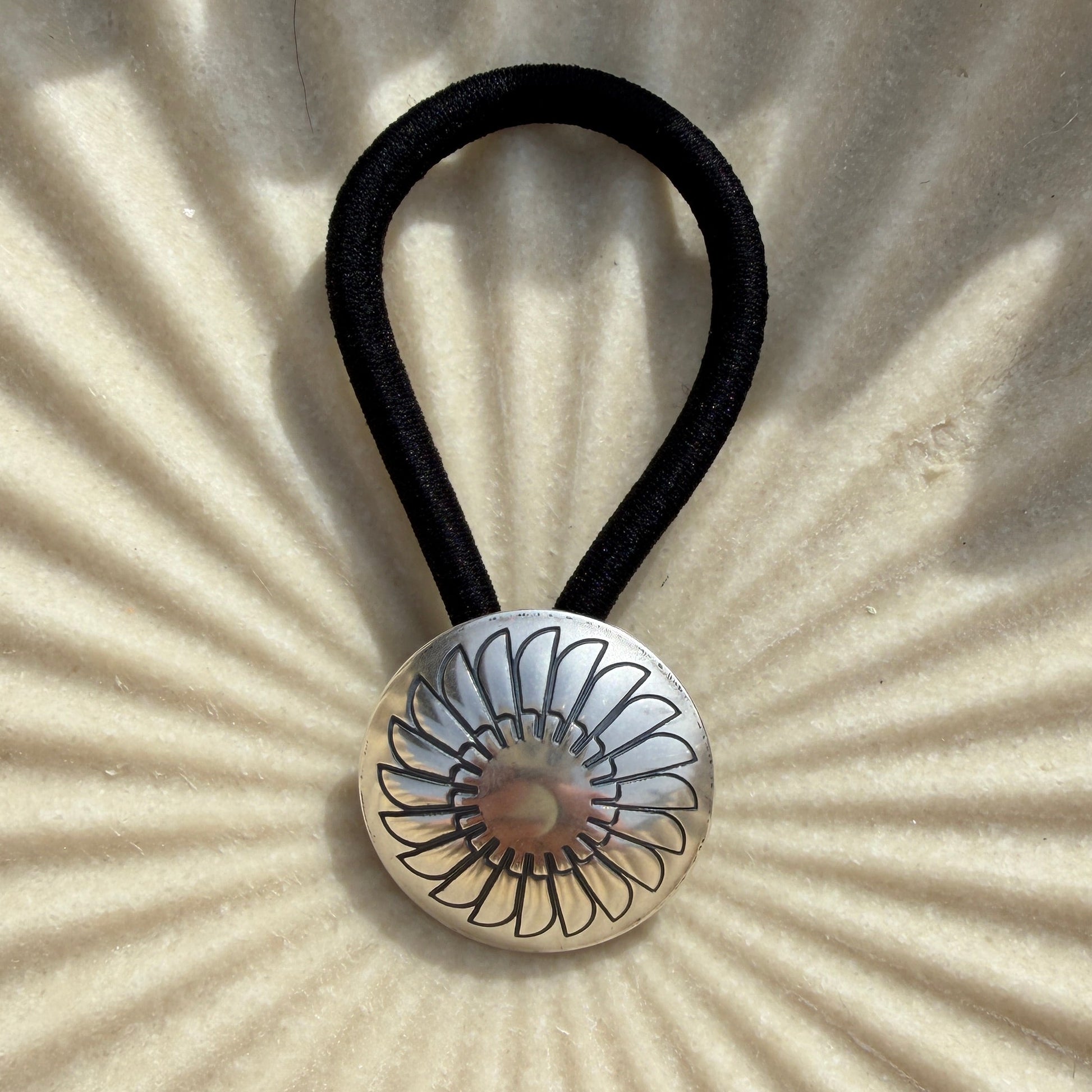 Hair tie with decorative button on a textured beige background