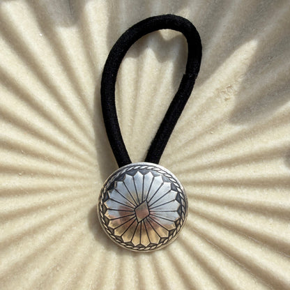Hair tie with decorative button on a textured beige background