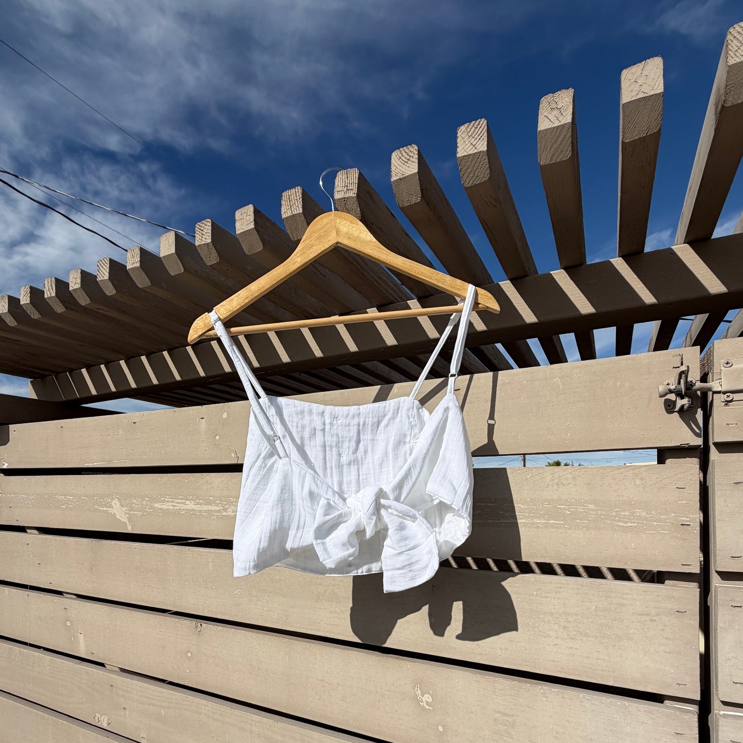 White shirt on a wooden hanger against a blue sky with windmill