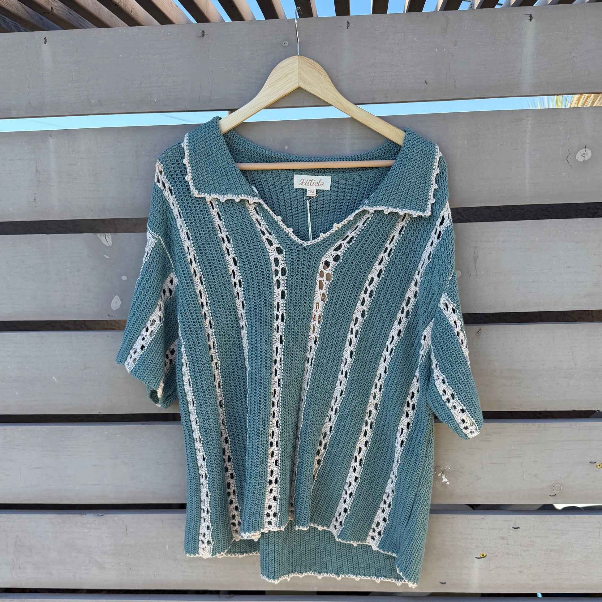 Green knit shirt on a hanger against a wooden background