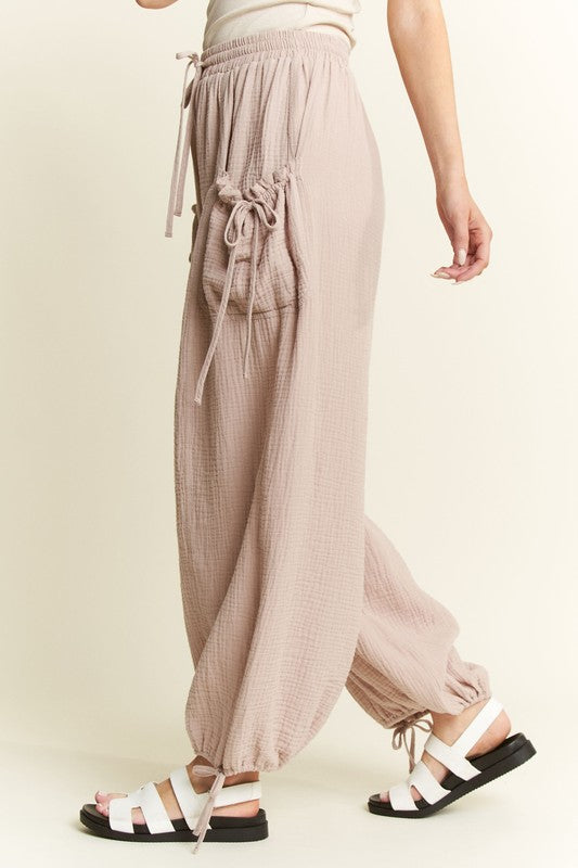 Person wearing light brown drawstring pants on a plain background